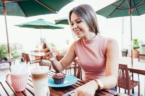 Ung kvinna äter frukost med kaffe och tårta sittandes outd — Stockfoto