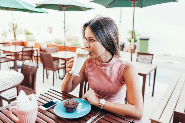 Mujer joven tomando un desayuno con café y pastel sentado fuera —  Fotos de Stock