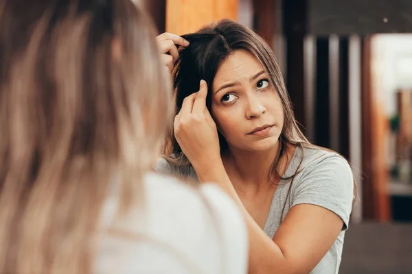 Young woman with hair loss problem looking in mirror at home — Stock Photo, Image