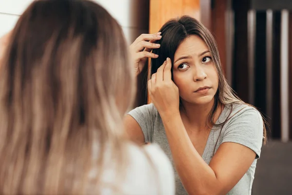Young woman with hair loss problem looking in mirror at home — Stock Photo, Image
