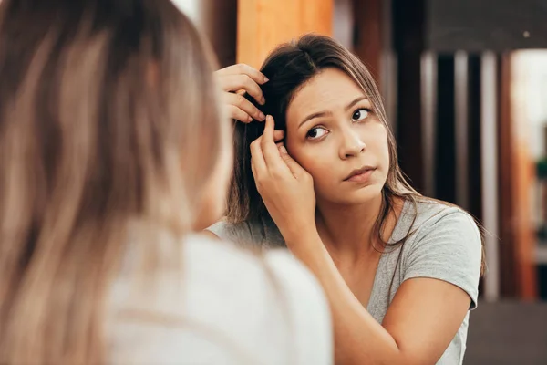 自宅の鏡で見ている脱毛の問題を持つ若い女性 — ストック写真