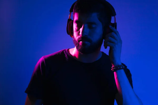 Неоновий світловий портрет бородатого чоловіка в навушниках. Прослуховування музики — стокове фото