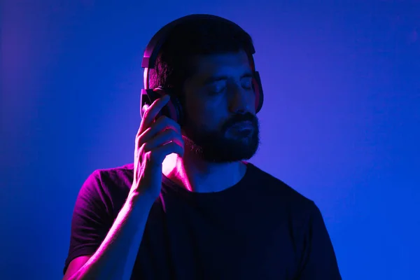 Neon light portrait of bearded man in headphones. Listening to music — Stock Photo, Image