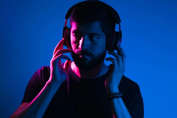 Retrato de luz de neón de hombre barbudo en auriculares. Escuchando a m — Foto de Stock