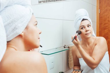 Banyoda genç kadın, kendini ferahlatıcı ve makyaj uygulayarak