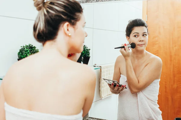 बाथरूममध्ये तरुण स्त्री, स्वत: ला ताजे करणे आणि मेकअप लागू करणे — स्टॉक फोटो, इमेज