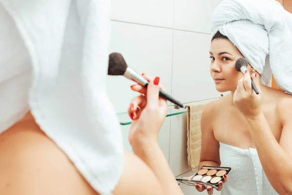 Jovem mulher no banheiro, refrescando-se e aplicando maquiagem — Fotografia de Stock