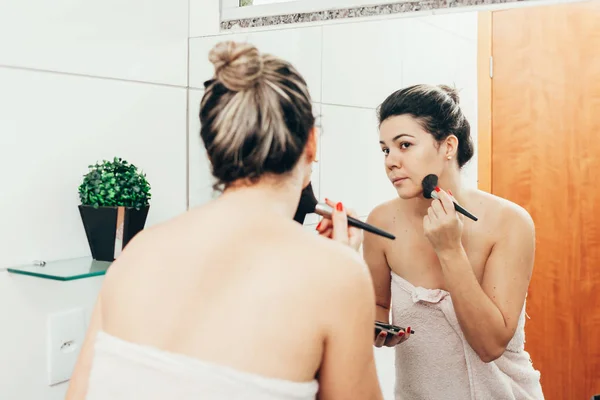 Jovem mulher no banheiro, refrescando-se e aplicando maquiagem — Fotografia de Stock