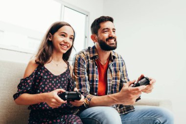 Gülümseyen baba ve kızı evde video oyun oynarken