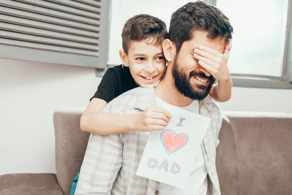 Happy father's day! Son congratulating dad and giving him a greeting card. Daddy and son smiling and hugging. Family holiday and togetherness. — Stock Photo, Image