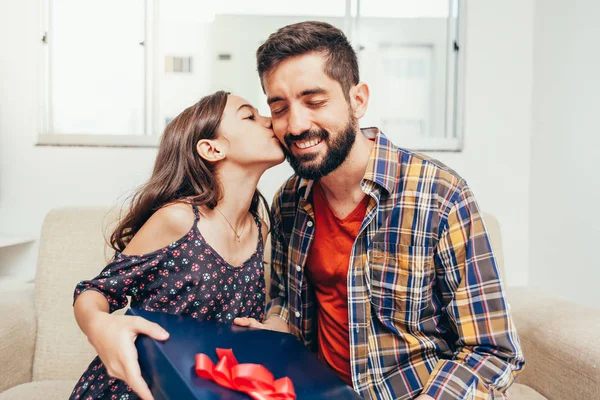 Glücklicher Vatertag! Tochter gratuliert Papa und schenkt ihm ein Geschenk. Papa und Tochter lächeln und umarmen sich. Familienurlaub und Zweisamkeit — Stockfoto