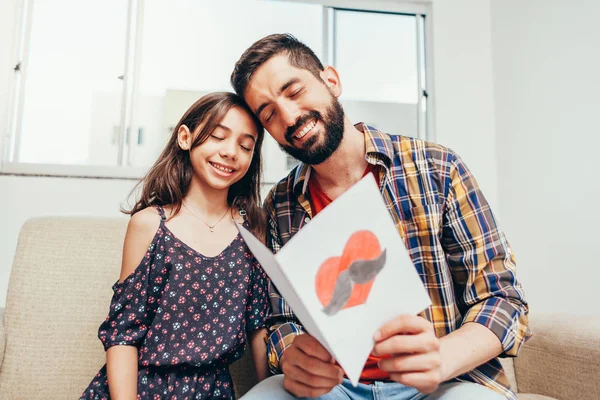 ¡Feliz día del padre! Hija felicitando a papá y dándole una tarjeta de felicitación. Papá y su hija sonriendo y abrazándose. Vacaciones familiares y unión — Foto de Stock