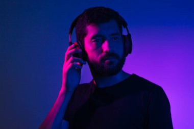 Kulaklıklı sakallı adamın Neon hafif portresi. M dinleme