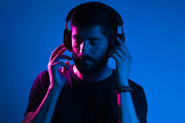 Neonlicht-Porträt eines bärtigen Mannes mit Kopfhörern. Musik hören — Stockfoto