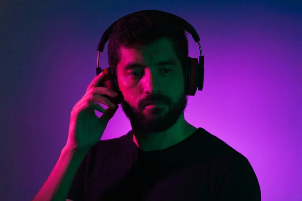 Retrato de luz de neón de hombre barbudo en auriculares. Escuchando música — Foto de Stock