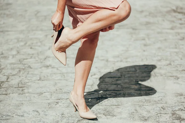 Close-up of the legs of a business woman who suffers from leg pain due to wearing  heels Stock Photo by borodai