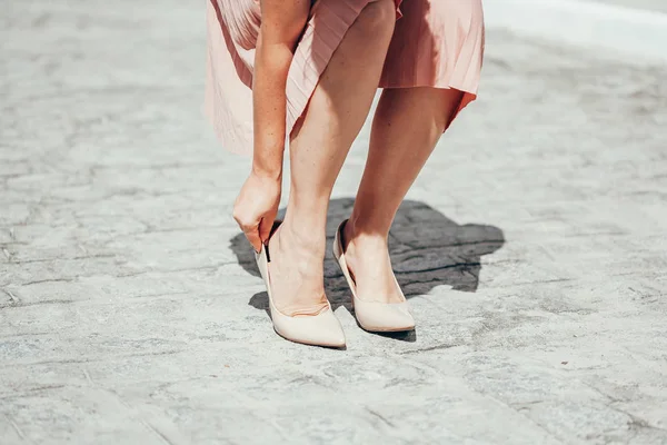 Frau leidet unter Beinschmerzen im Freien wegen unbequemer Schuhe. — Stockfoto