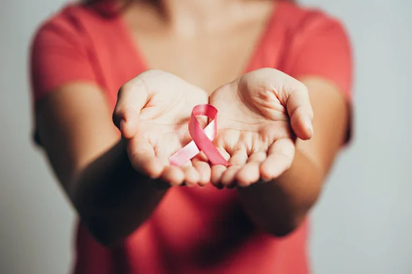 Hälso-och sjukvård koncept - kvinnor händer som håller rosa bröstcancer medvetenhet band — Stockfoto