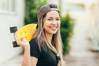 Onu kaykay ile gülümseyen genç kadın kaykaycı Portresi