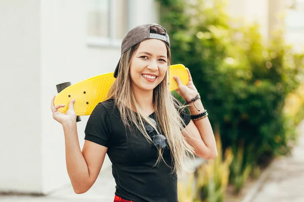 Portret van lachende jonge vrouwelijke skateboarder met haar skateboar — Stockfoto
