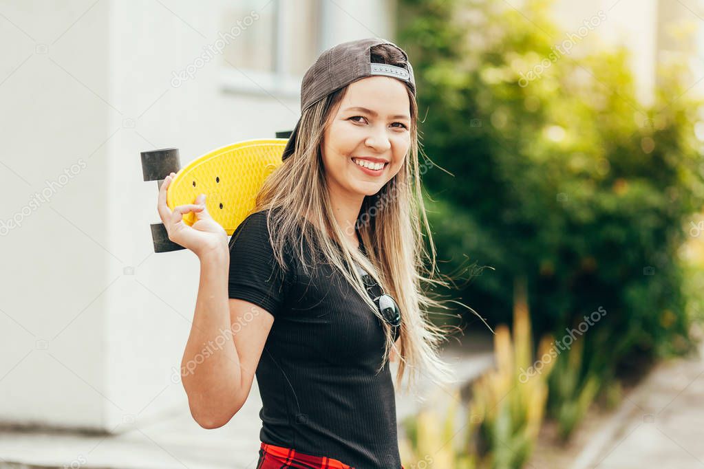 Portrait of smiling young female skateboarder with her skateboar