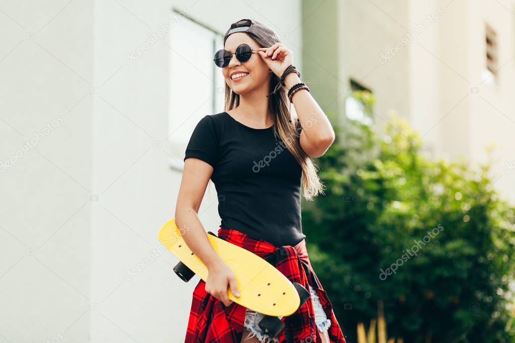Portrait of smiling young female skateboarder with her skateboar