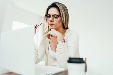 Evde dizüstü bilgisayarda çalışan güzel bir kadın.