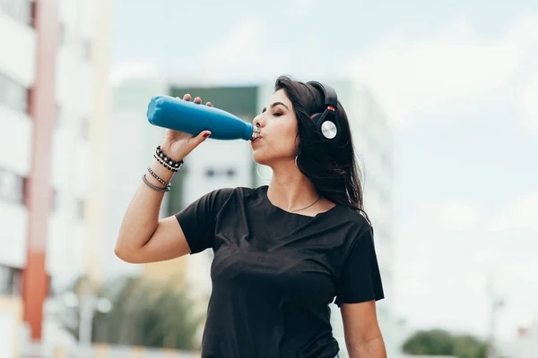 Beautiful young woman using headphone listening to music and dri — Stock Photo, Image