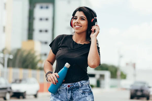Молодая женщина с помощью наушников слушает музыку и пьет — стоковое фото
