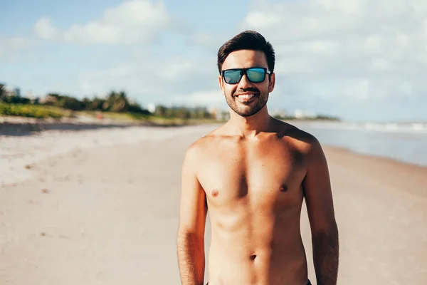 Портрет усміхненого красивого чоловіка, що стоїть на тропічному пляжі. Літні канікули — стокове фото
