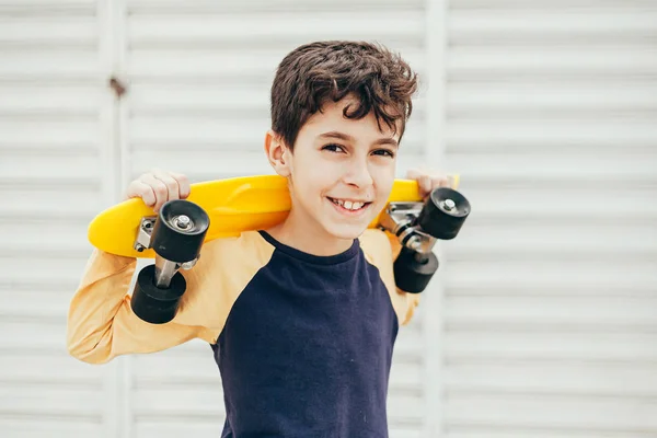 Portrait of 9 year old boy holding skateboard outdoors — Stock Photo, Image