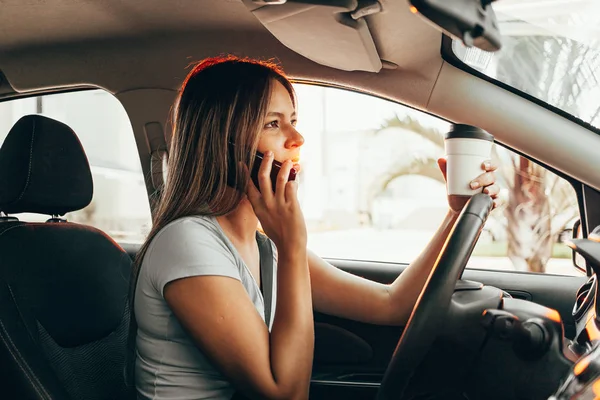 Mulher está no telefone e beber café enquanto dirige o carro — Fotografia de Stock