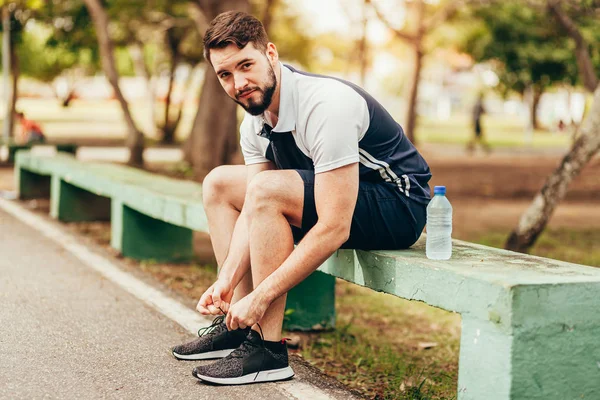 Ung löpare sitter i Public Park binda sina skosnören — Stockfoto