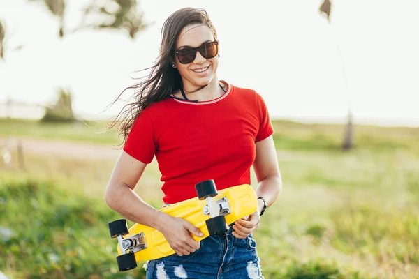 Mulher bonita com skate na praia — Fotografia de Stock