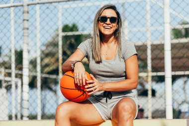 Spor salonundaki kadın basketbol antrenmanından sonra dinleniyor. Spor yapan kadın spor yaparken rahat ve oturaklı giyinir.