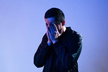 Utangaç bir adam yüzünü polis arabasının ışıklarıyla kapatıyor.