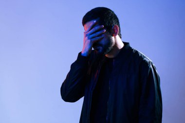 Utangaç bir adam yüzünü polis arabasının ışıklarıyla kapatıyor.