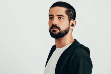 Spor kıyafetleri ve kablosuz kulaklık takan sakallı bir adamın portresi..