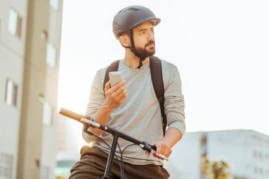 Bisikletçi, şehirde akıllı telefonuna bakıyor. GPS haritası veya dağıtım uygulamaları kullanma kavramı
