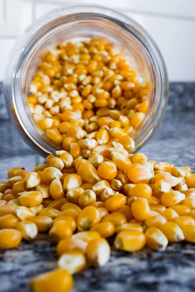 Maïs gebruikt om popcorn uit een glazen pot te laten komen, maar niet gekookt — Stockfoto