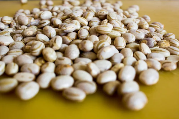 Dry and uncooked brown beans with a warm and yellow background