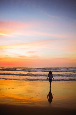 Ubatuba, Sao Paul gün doğumunda sahilde yürüyen genç kadın