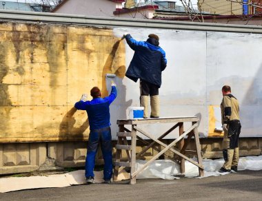 Tulum üç ressam elle gri eski bir ahşap duvar boya