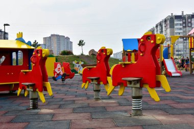 Bahçesi kauçuk kaplama ile konumlar genç çocuklar için oyun. Springsswing metal bir sarmal üzerinde atlarla 