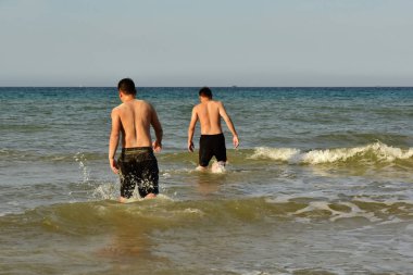 4 Temmuz 2018. Cam Ranh. Vietnam. İki erkek siyah şort, okyanus dalgaları ile zaman uyumlu olarak girin. Yıkanmak için arzu. Şehirde ısı. Sağlıklı bir yaşam tarzı. Arkadan görüntülemek