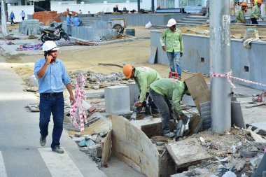 12 Temmuz 2018. Nha Trang. Vietnam. Otel Kompleksi İnşaatı Genel işçiler. Baş mühendis, Müdür, Müfettiş telefonda konuşurken bir beyaz kask içinde. İnşaat denetler