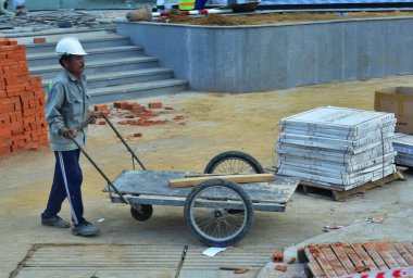 12 Temmuz 2018. Nha Trang. Vietnam. Otel Kompleksi İnşaatı Genel işçiler. Bir adam inşaat malzemeleri taşımak için bir kamyon ile beyaz bir kask küçük boy