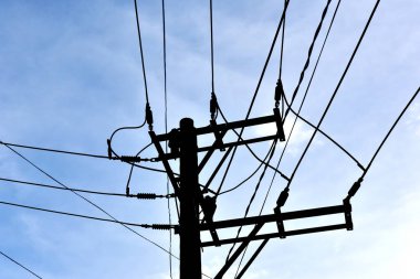 Teller ve kablolar bir mavi gökyüzü arka plan ile bir elektrik direği silüeti