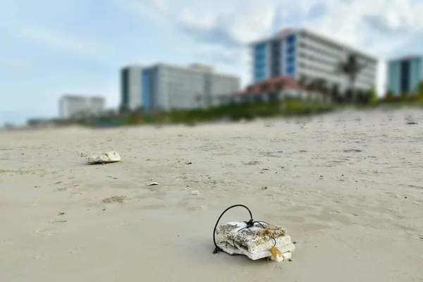 Self-made white  buoy a tied to a rope confused network fishing fish on a wet sand beach fishing village. Garbage thrown ashore by waves. Dump in the resort area amidst the blurred buildings of hotel