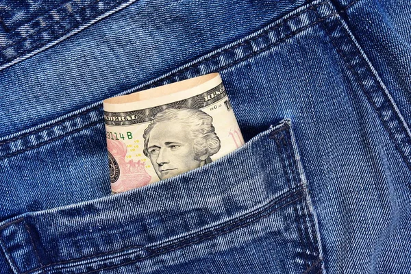 The president Hamilton on a 10 dollar bill peeps out of his jeans pocket. Concept on the topic of illegal work.